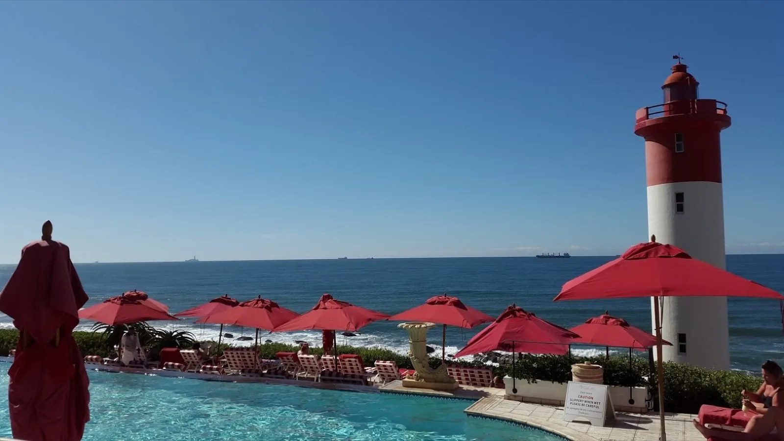 Red umbrellas at the pool with the lighthouse behind