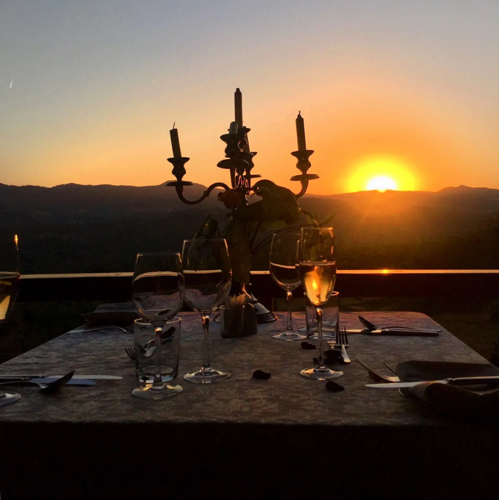 A table laid outside at sunset, candelabra lit