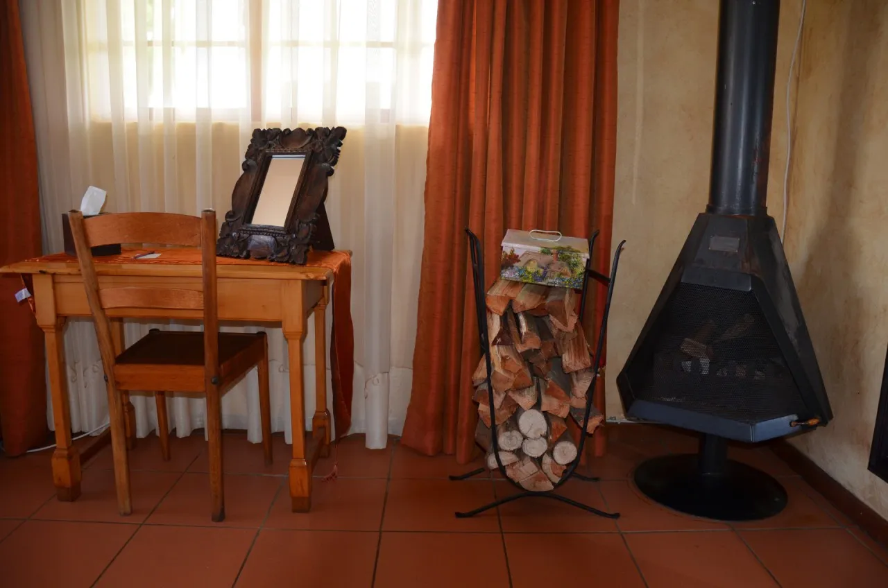A writing desk beside the room's fireplace and stacked logs