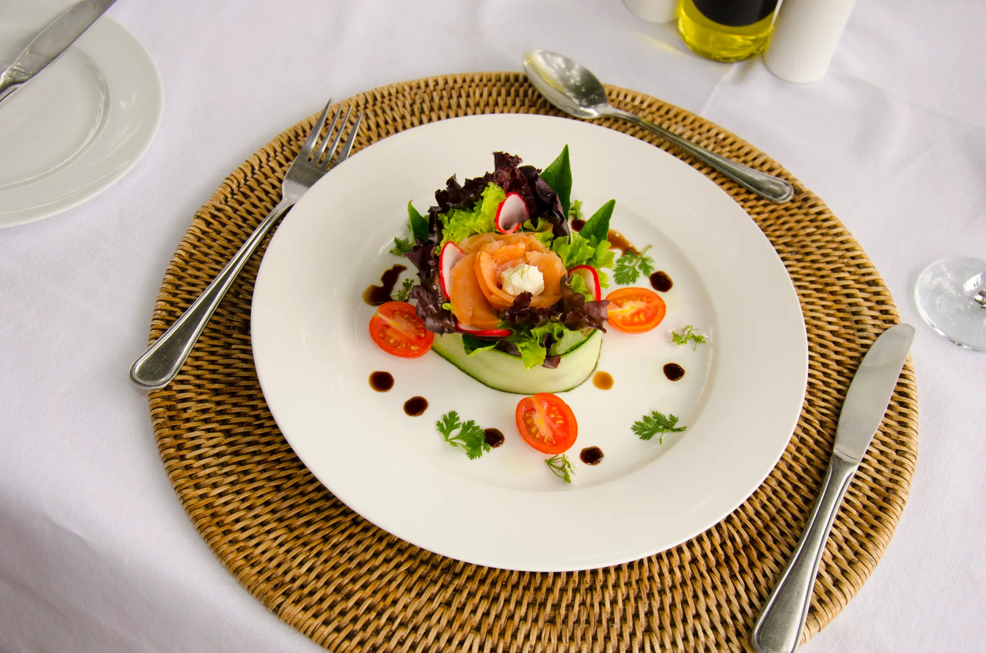 A plated salad starter set on a woven mat
