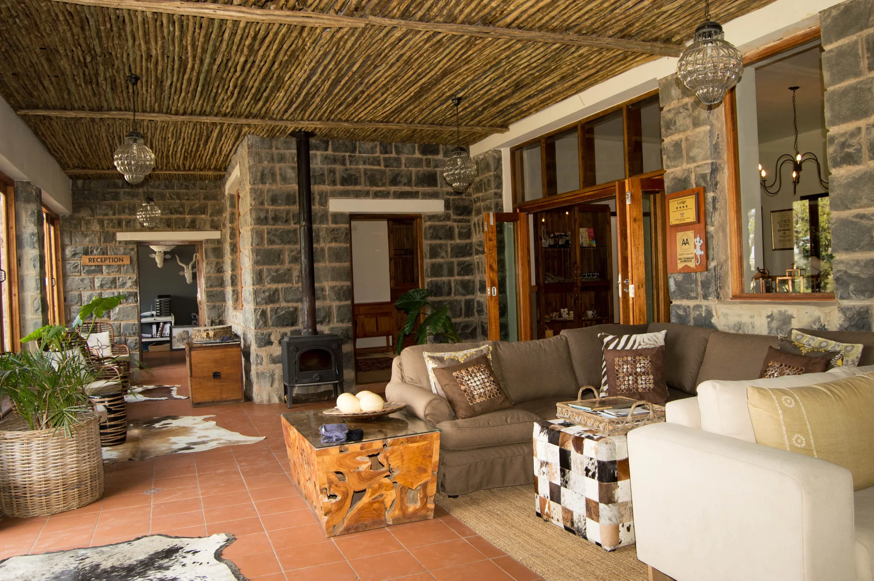 The lodge lounge — stone walls, deep sofas and a fireplace under a reed ceiling