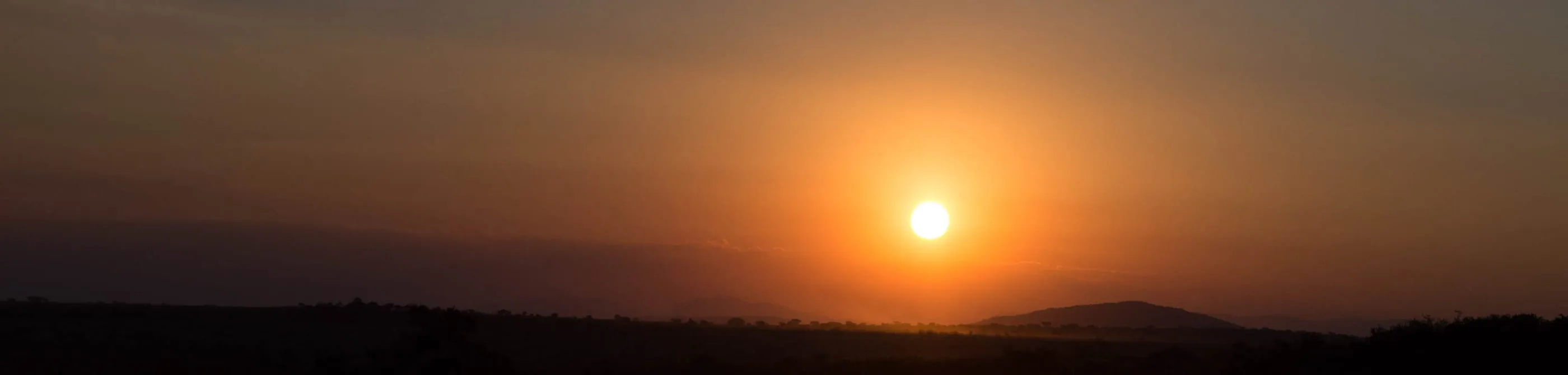 The sun dropping behind the hills at the end of an afternoon drive