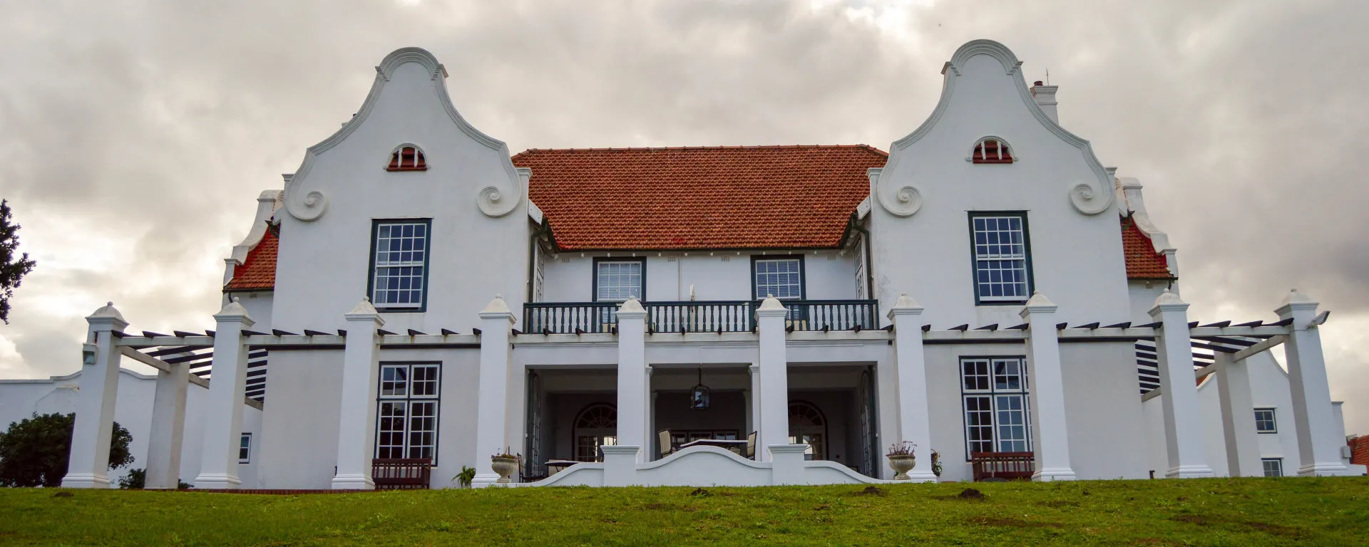 The full frontage of the house, gabled and white on a green lawn