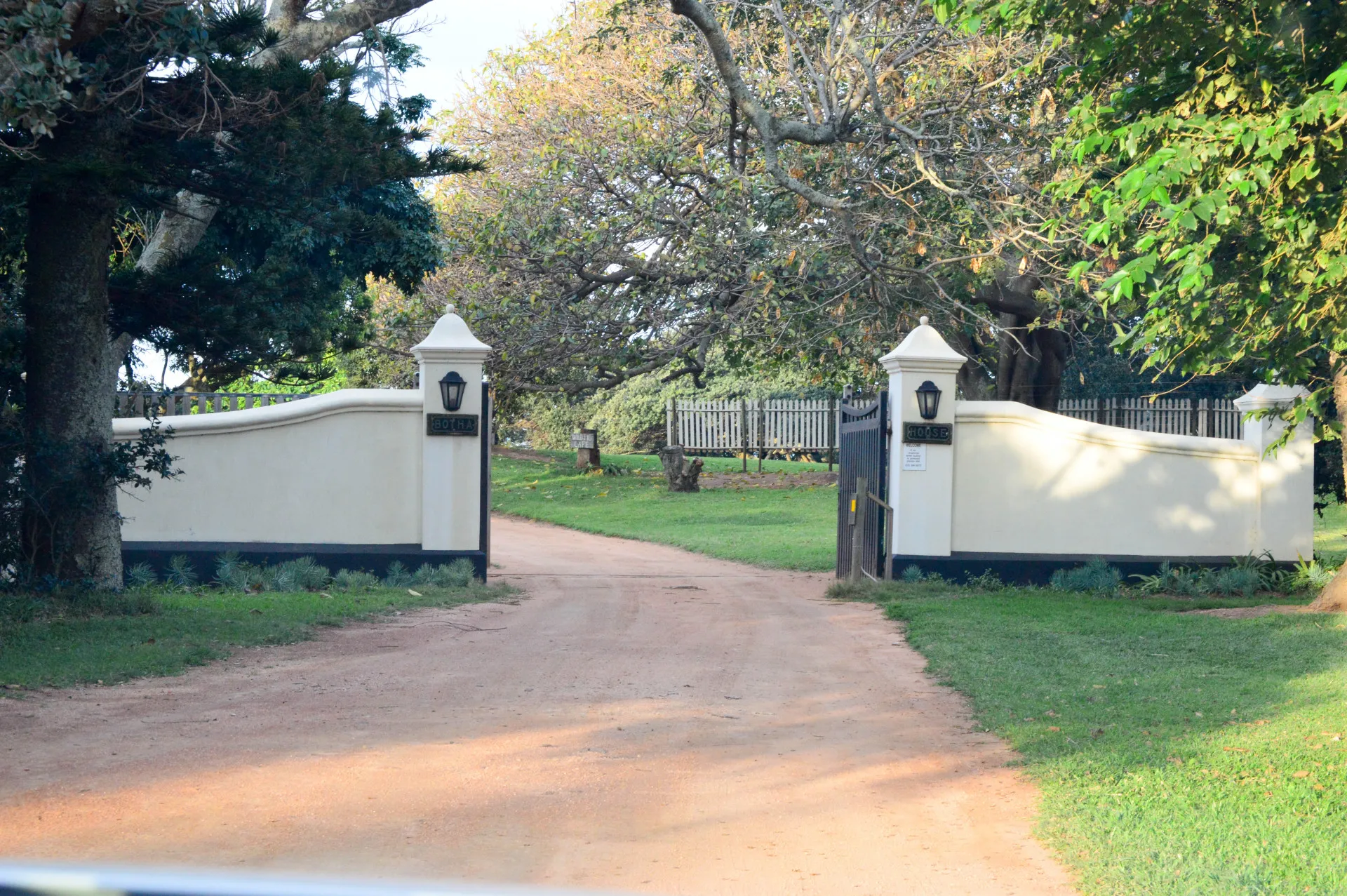 The gated driveway leading in under the trees