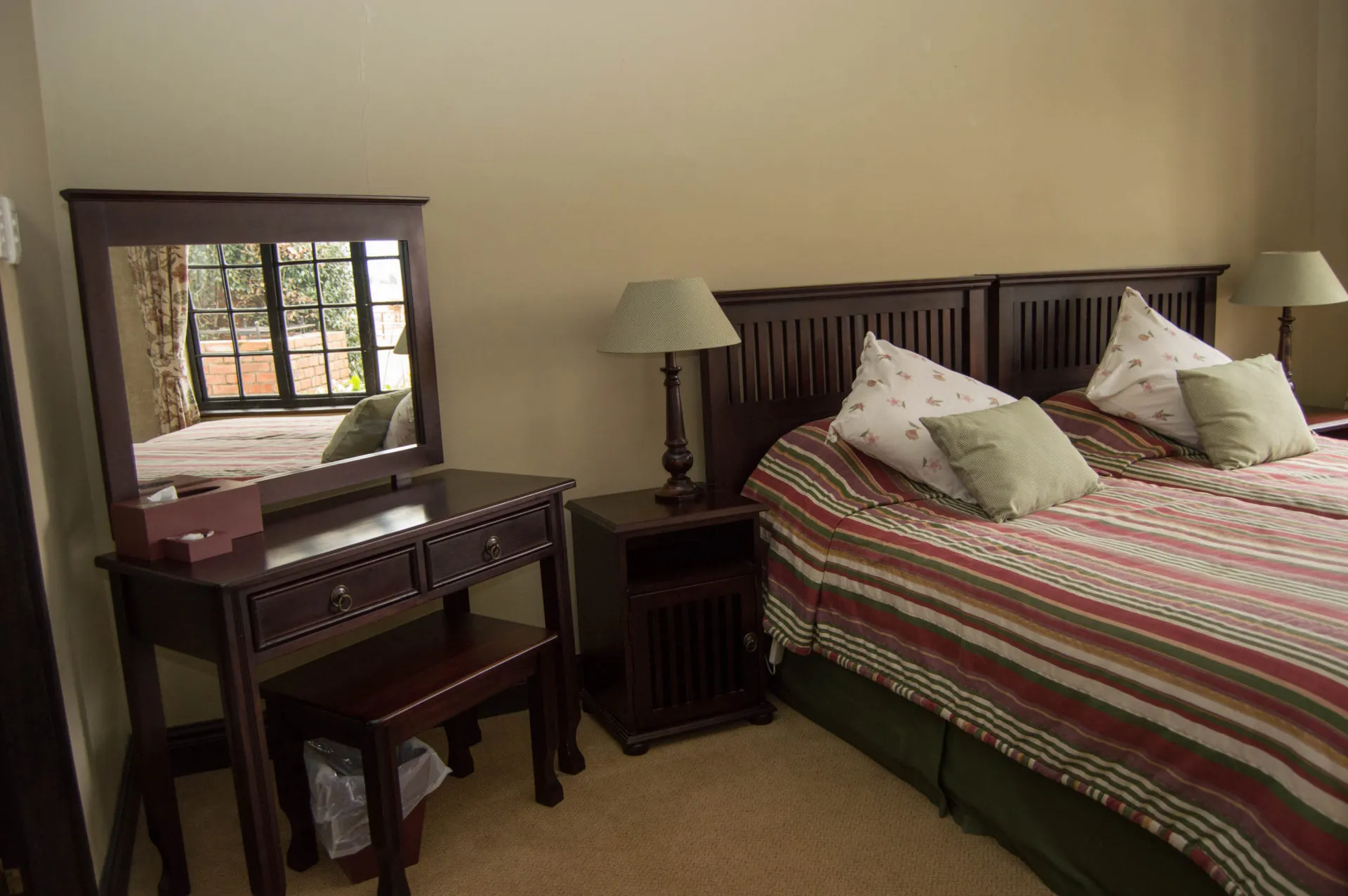 A bedroom with a wooden bed and a striped runner across the foot