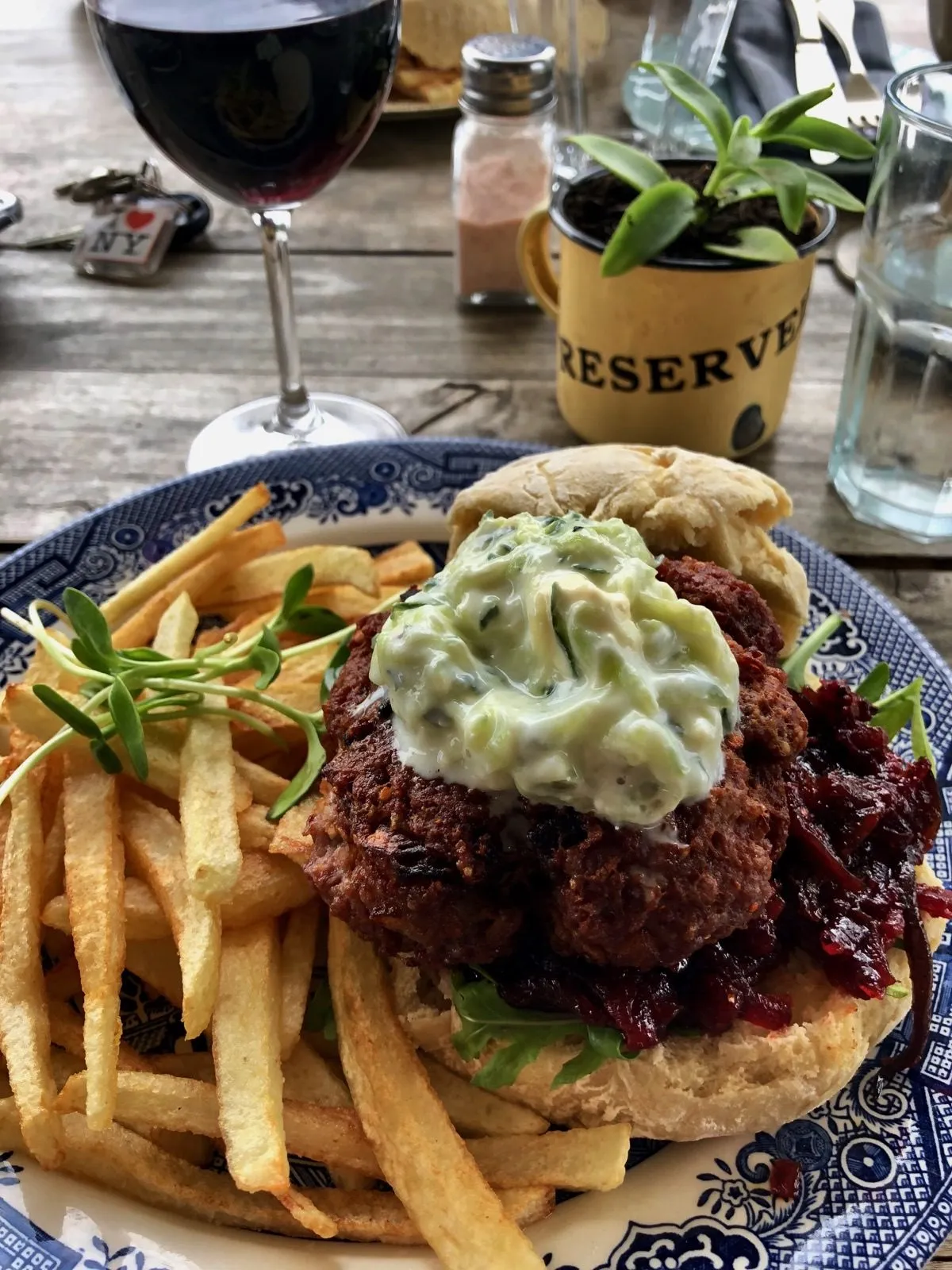 A burger and chips with a glass of red