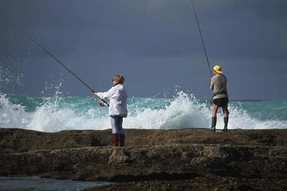 Two anglers casting off the rocks into the surf