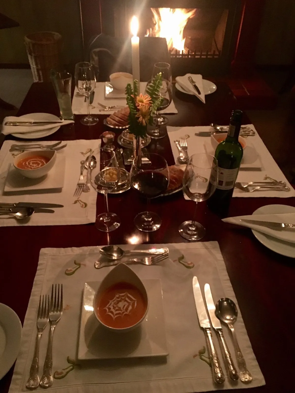 A table laid for dinner with a fire behind