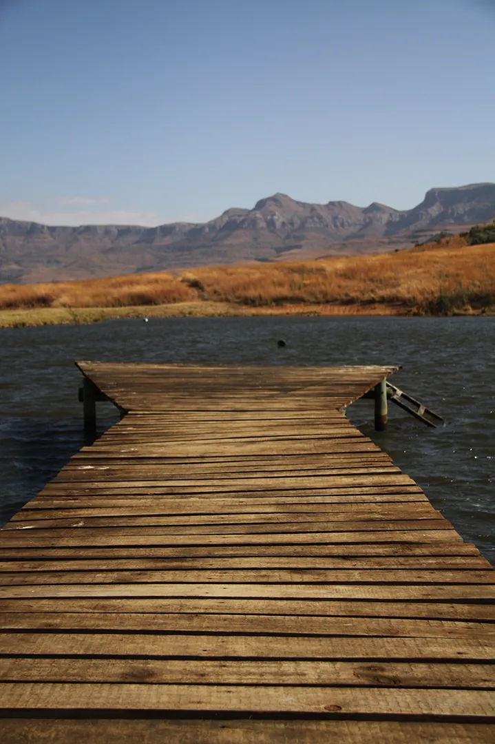 A wooden jetty running out onto the trout dam below the mountains