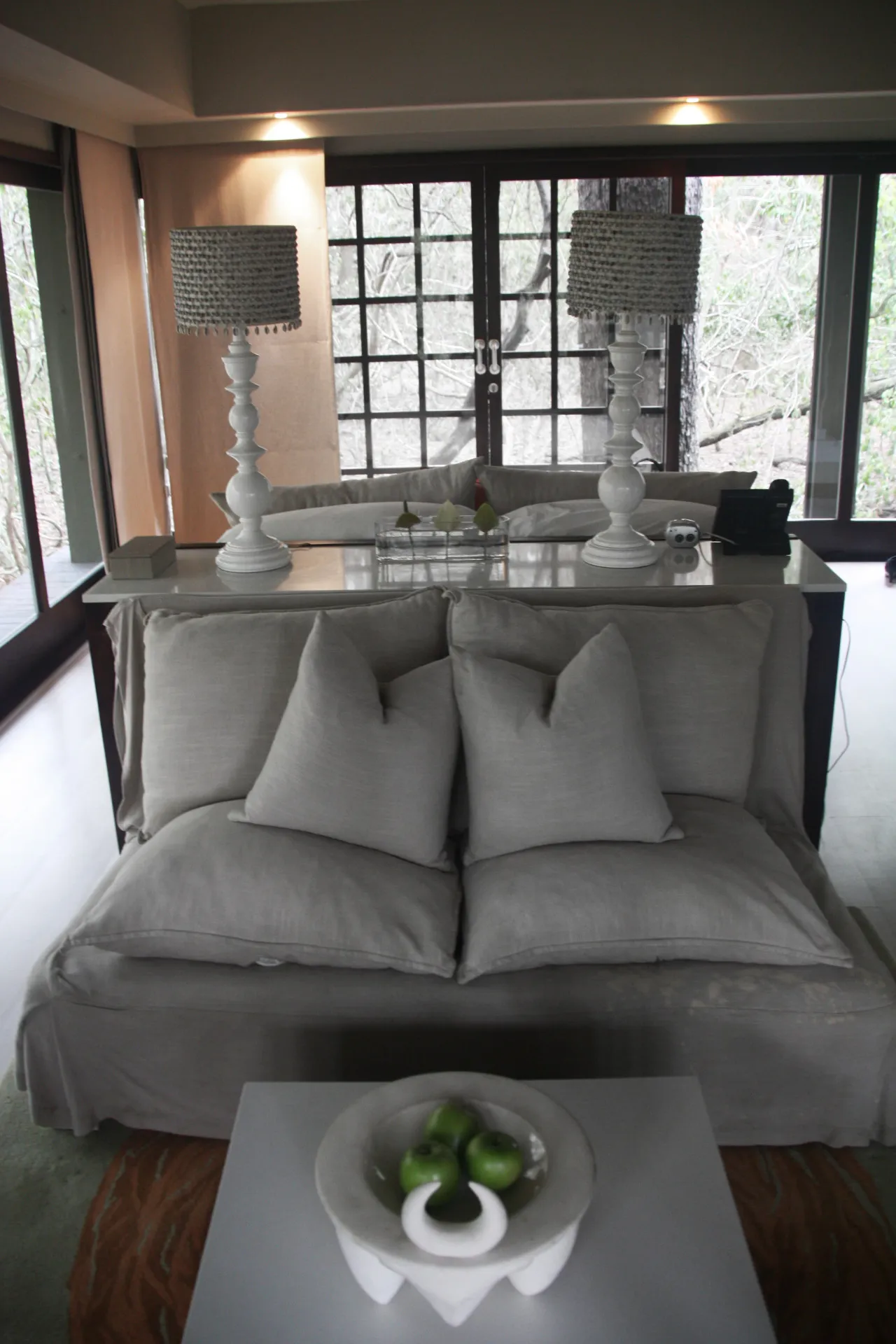 The bedroom inside the suite, pale and quiet with the forest beyond the glass